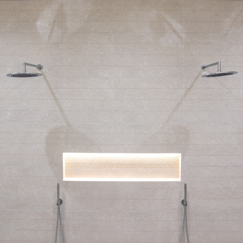 Shower with two chrome rain shower heads, shelf recess and textured beige wall tiles. 