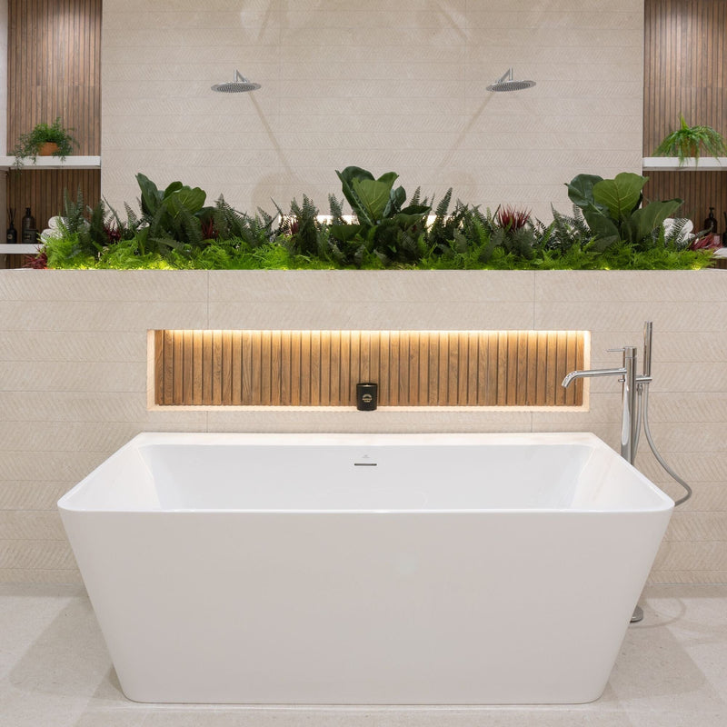 Modern bathroom with a white freestanding bathtub, beige tiles and green plants.