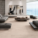 Modern living room with a grey sofas, a round wooden coffee table, abstract wall art and beige floor tiles.
