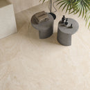 Small grey round tables on large beige travertine effect floor tiles.