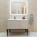 Bathroom vanity with illuminated mirror and towel hanging on a wall.