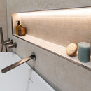 Bathroom setting with a bathtub, tap and shelf with toiletries.