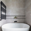Modern bathroom with a white freestanding bathtub, black towel radiator, and recess 